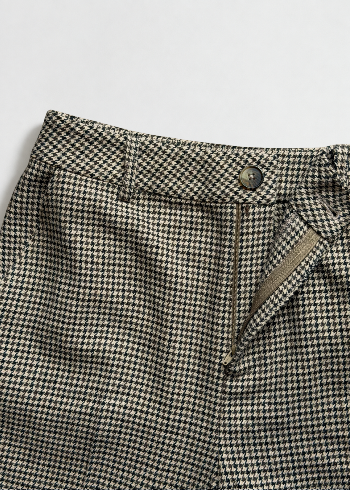 Close-up of the Brock trouser waistband showing the front button, belt loops and open zip