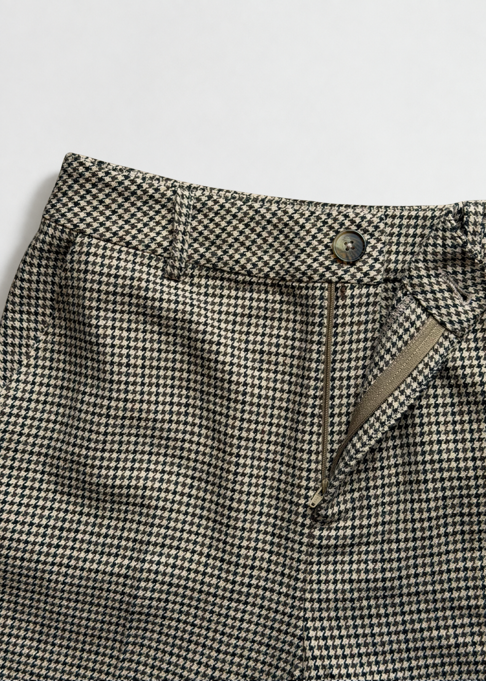Close-up of the Brock trouser waistband showing the front button, belt loops and open zip