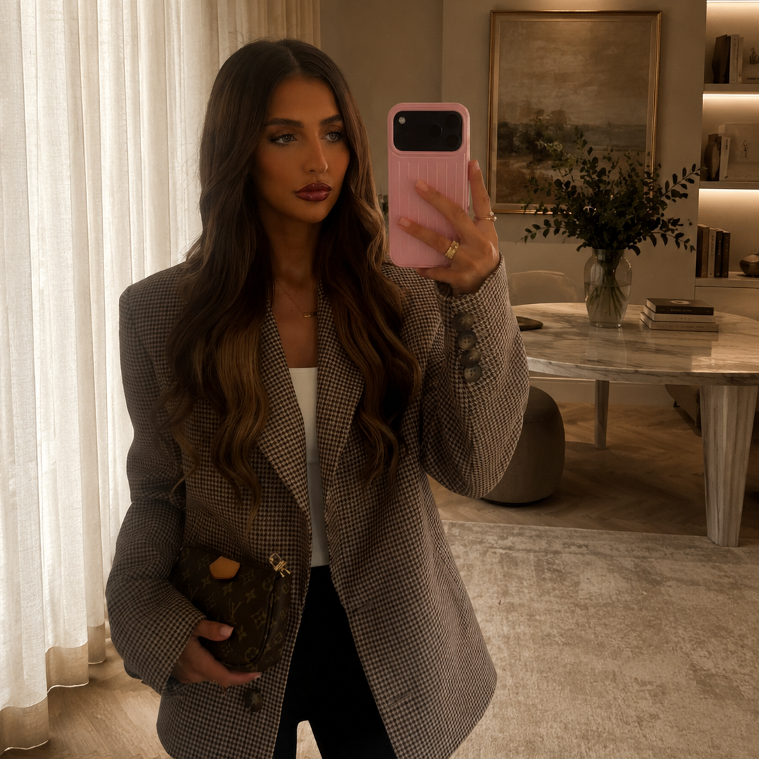 Woman taking a mirror photo in the Brock houndstooth blazer with black trousers and a black handbag.